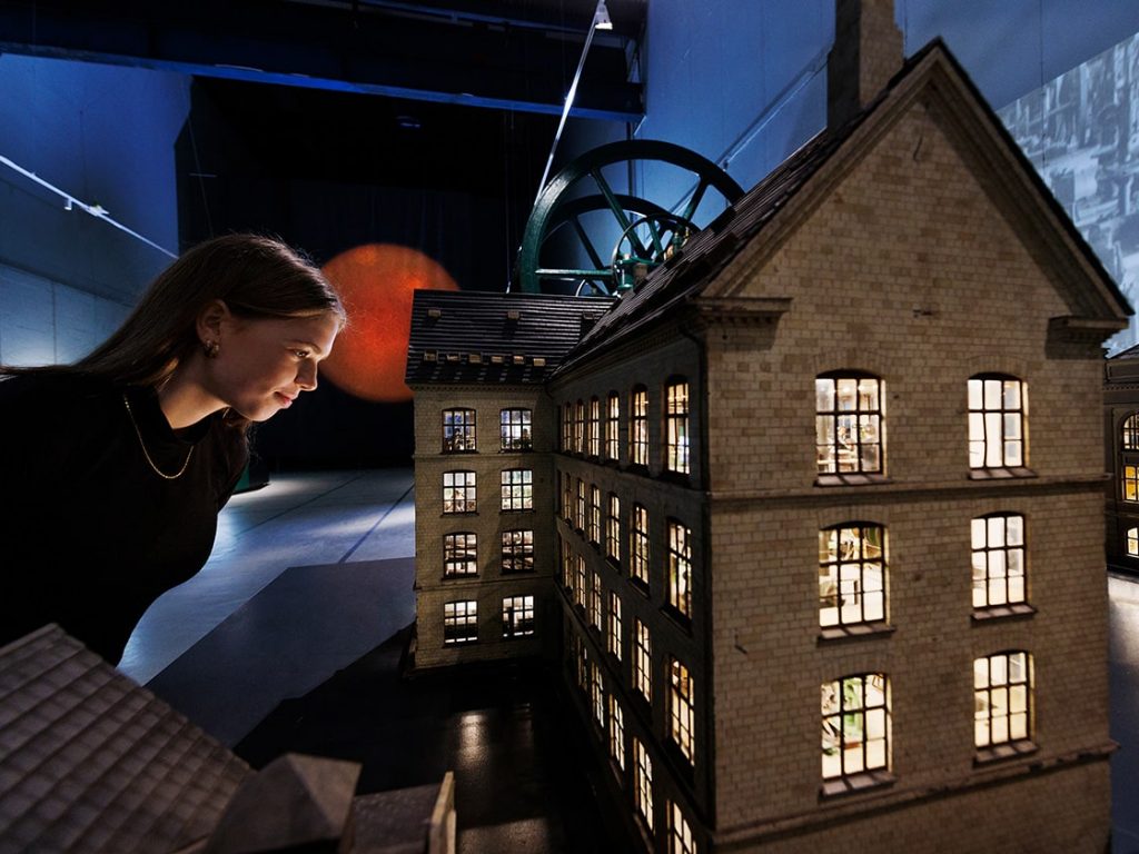 Ung kvinde ser på fabriksmodel. Danmarks Tekniske Museum. Fotograf Miklos Szabo 1140x840px